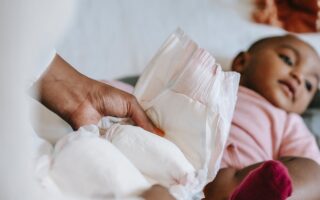 Kobieta zmienia pieluszke swojemu dziecku i używa odpowiednich kosmetyków